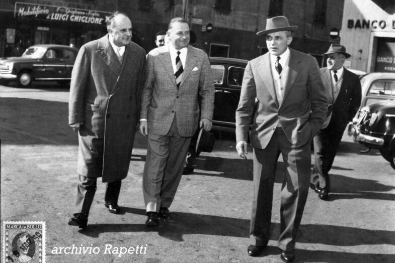Marzo 1959: Adriano Rodoni, presidente FCI, Alfredo Binda, Commissario Tecnico e Luigi Ghiglione in piazza Pontedecimo discutono del prossimo Giro dell’Appennino, il XX. Sullo sfondo l’indicazione del mobilificio di Luigin.